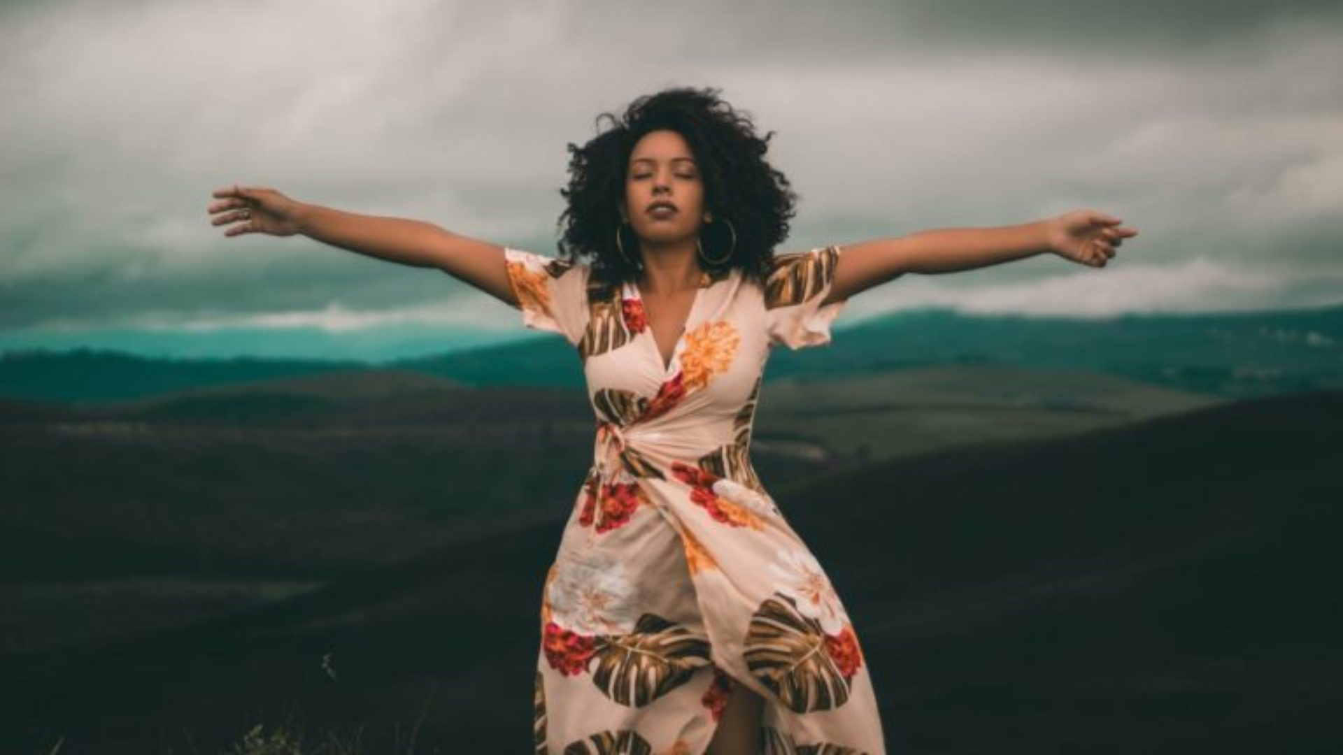 Mujer con los brazos extendidos en plena naturaleza, simbolizando la libertad emocional que se trabaja en las sesiones de psicoterapia.